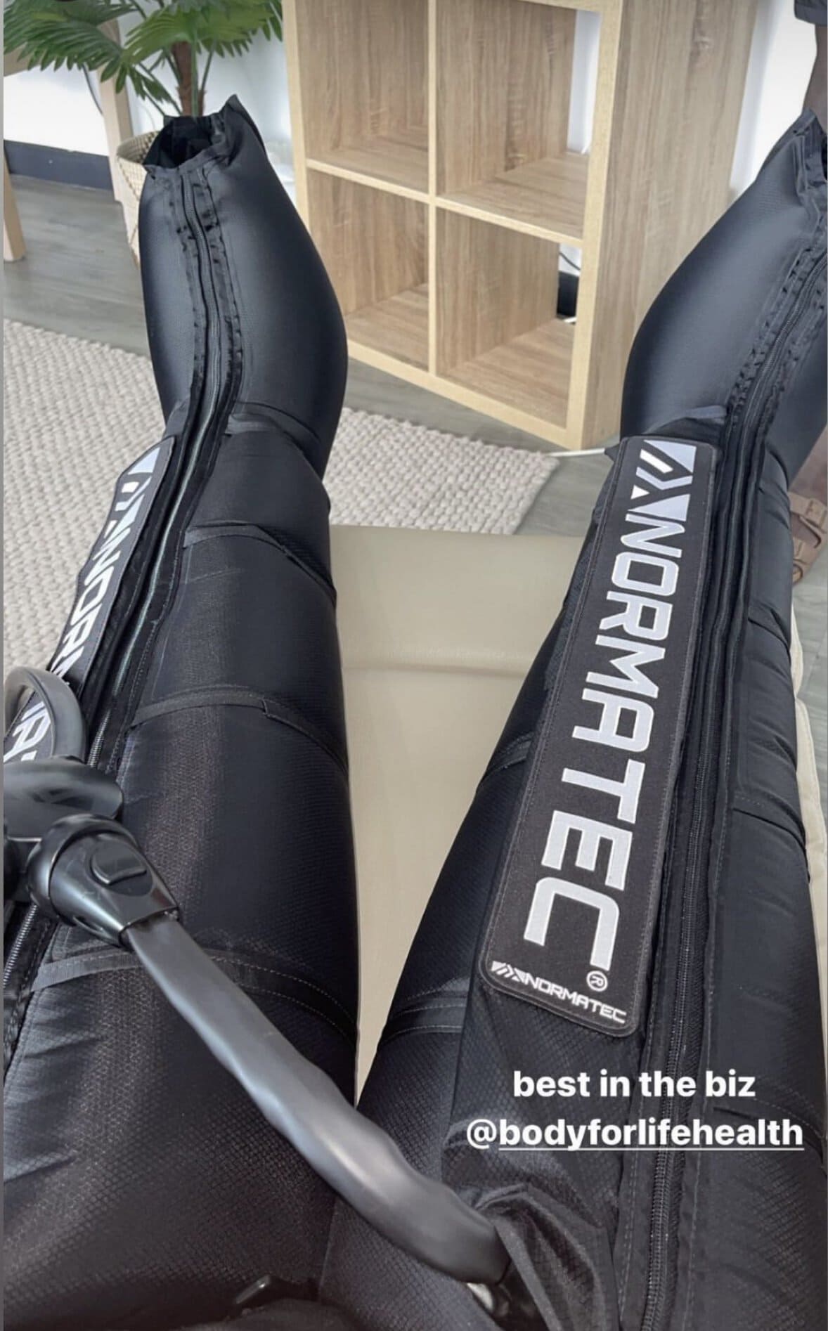 NormaTec boots laid out in front on a recliner chair