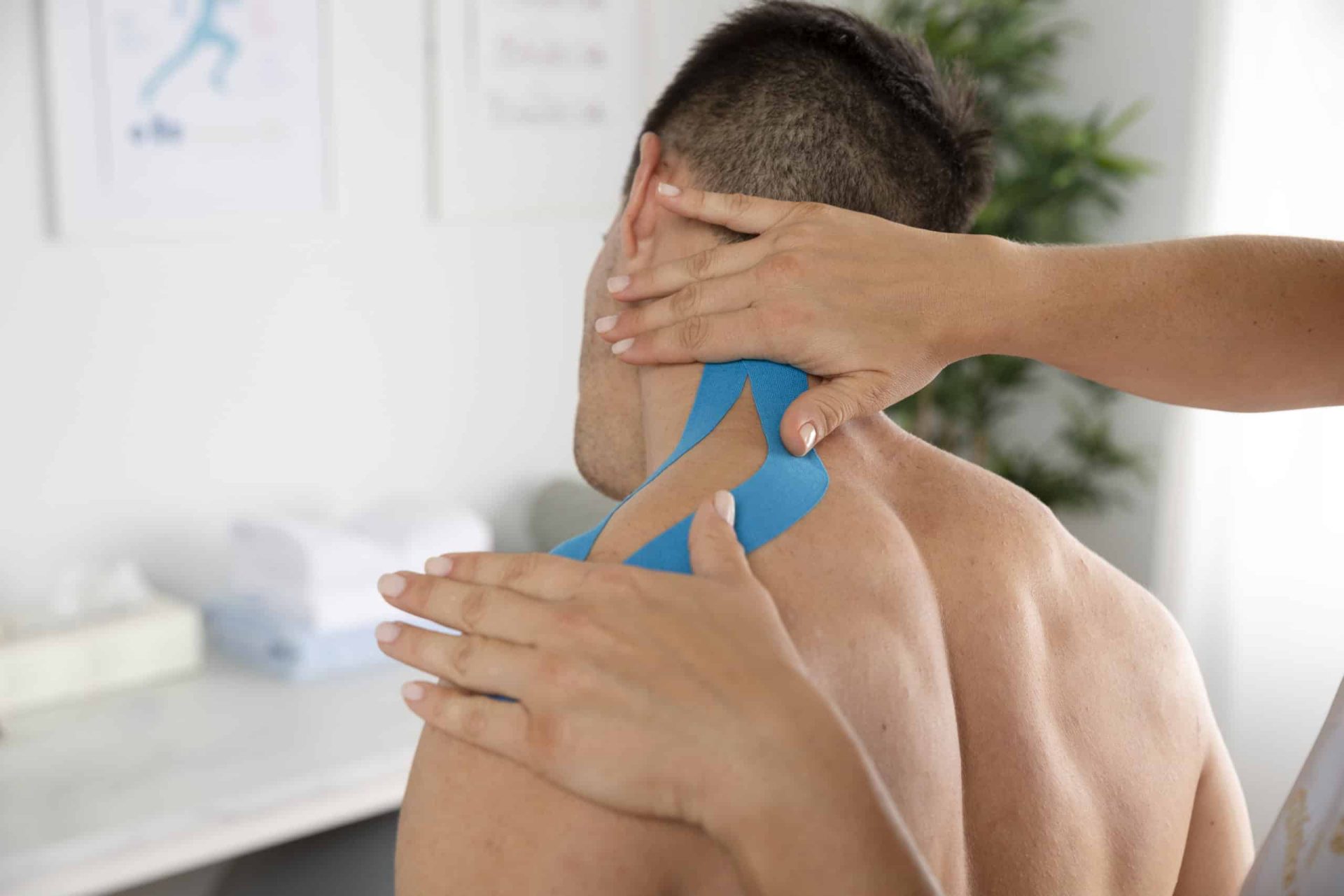 Physiotherapist applying sports strapping to mans shoulder